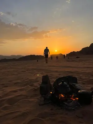 a man walking on the beach with a motorcycle in the sand at Wadi Rum Mirror Camp in Wadi Rum