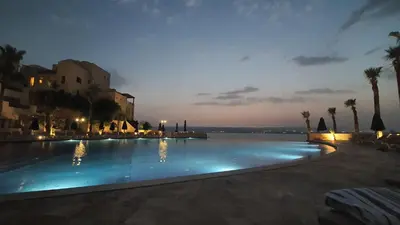a swimming pool at night with a view of the water at Comfy Stays Sea View Apartments at DeadSea Samarah Resort in Sowayma