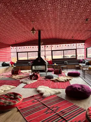 a large room with a fireplace and pillows on the floor at Bedouin Yoga & Trekking Camp Wadi Rum in Wadi Rum