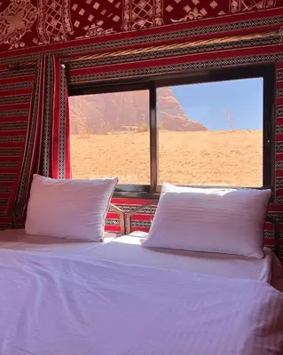 a bed with white pillows in a room with a window at Bedouin Yoga & Trekking Camp Wadi Rum in Wadi Rum