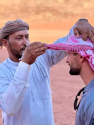 a man is putting a hat on another mans head at Bedouin Yoga & Trekking Camp Wadi Rum in Wadi Rum