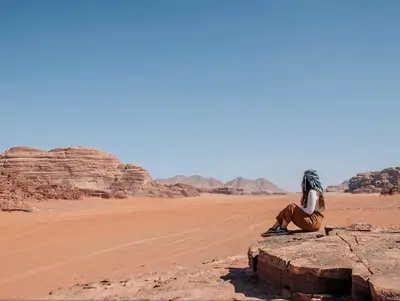 a woman sitting on a rock in the desert at rum rema camp in Wadi Rum