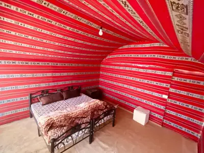 a bedroom with a red and white stripped wall at Wadi Rum Trail in Wadi Rum