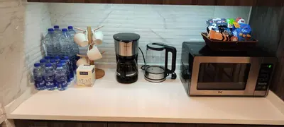 a kitchen counter with a microwave and bottles of water at Amazing Studio in DAMAC in Amman