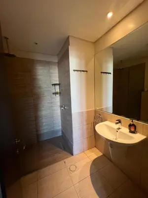 a bathroom with a sink and a shower with a mirror at Spacious apartments with Sea view at Samarah Resort in Sowayma