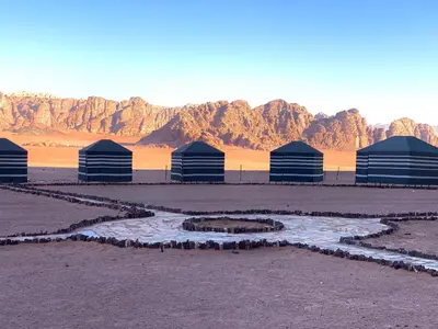 a group of buildings in the desert with mountains in the background at Bedouins nights in Wadi Rum