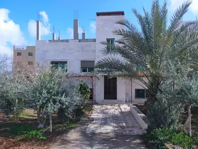 a building with a palm tree in front of it at Maria Home in Madaba