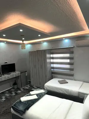 a bedroom with two beds and a desk with a computer at Petra Pillars Way Hostel in Wadi Musa