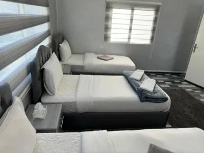 a room with three beds and a window at Petra Pillars Way Hostel in Wadi Musa
