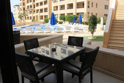 a glass table and chairs on a balcony with a pool at Samarah Dead Sea Resort Studio-CP6 Traveler Award 2026 Winner Thursday, Friday and Saturday Groups consisting solely of male guests are not permitted in Sowayma