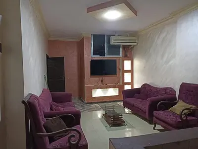 a living room with purple couches and a tv at Economic Apartment in Az Zarqa
