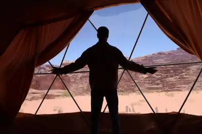 a man standing inside a tent looking out at the desert at Wadi rum Bubble Camp & tour in Wadi Rum
