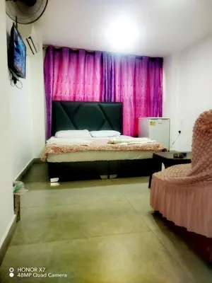 a bedroom with a bed and pink curtains at Farah Plaza Hostel &Hotel Apartments in Aqaba