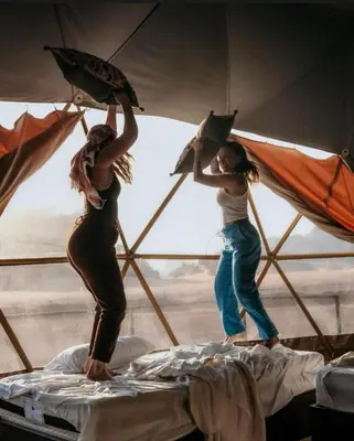 two girls are standing on a bed with umbrellas at Mountain Magic Camp Wadi Rum in Wadi Rum