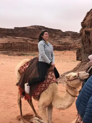 a woman riding a camel in the desert at Mountain Magic Camp Wadi Rum in Wadi Rum