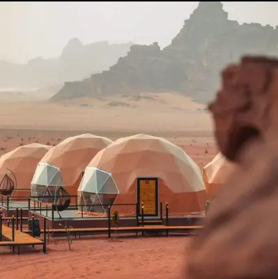 a row of tents in the desert with mountains in the background at Mountain Magic Camp Wadi Rum in Wadi Rum