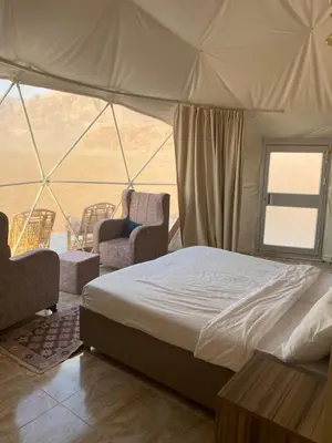 a bedroom with a bed and chairs in a tent at Qimam Al Sarab Camp Wadi Rum in Wadi Rum