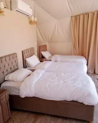 two beds in a room with a tent at Qimam Al Sarab Camp Wadi Rum in Wadi Rum