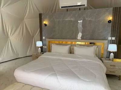 a bedroom with a large white bed and two lamps at Qimam Al Sarab Camp Wadi Rum in Wadi Rum