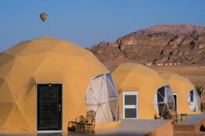 a group of three dome tents in the desert at Qimam Al Sarab Camp Wadi Rum in Wadi Rum