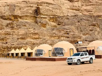 a white truck parked in front of a mountain at Rum Four Seasons luxury Camp & Jeep Tours in Wadi Rum