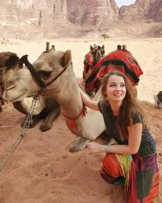 a young woman is petting a camel in the desert at Bedouin Memories Camp in Wadi Rum