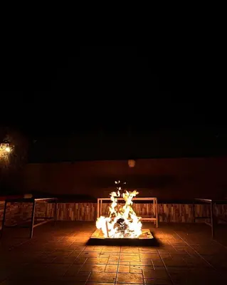 a fire in the middle of a patio at night at Wadi Rum Trip Bedouin Camp in Wadi Rum