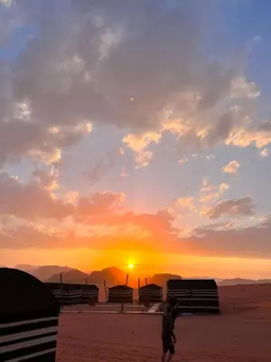 a person walking on the beach at sunset at Wadi Rum Trip Bedouin Camp in Wadi Rum