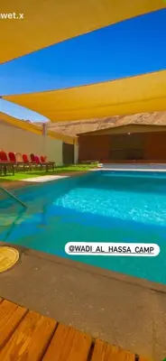 a swimming pool in a building with red chairs at Wadi Al-Hassa camp in Khawkhah
