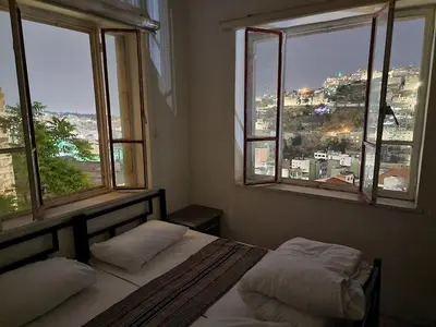 a bedroom with two beds and two windows at Rainbow Guest House in Amman