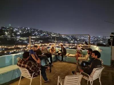 a group of people sitting on a rooftop at night at Rainbow Guest House in Amman