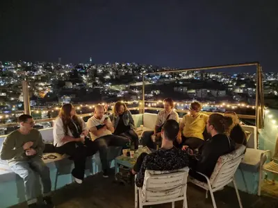 a group of people sitting on a balcony at night at Rainbow Guest House in Amman