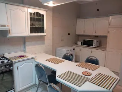 a kitchen with white cabinets and a table and chairs at Abdoun ground floor apartment in Amman