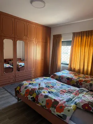 a bedroom with two beds and wooden cabinets at Abdoun ground floor apartment in Amman