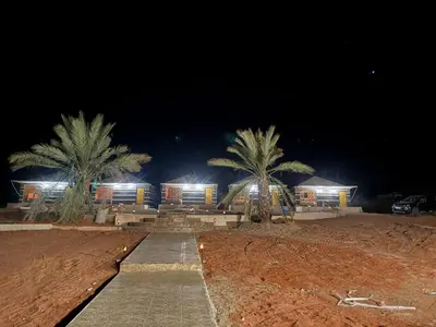 a building with palm trees in front of it at night at falling Stars Camp in Wadi Rum