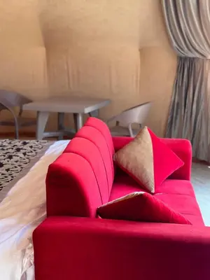 a red couch with pillows on a bed at Sandy Camp Wadi Rum in Wadi Rum