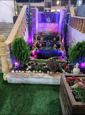 a fountain in a garden with purple lights at Shihan hotel suites in Amman