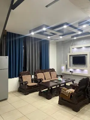 a living room with chairs and a table and a tv at Shihan hotel suites in Amman