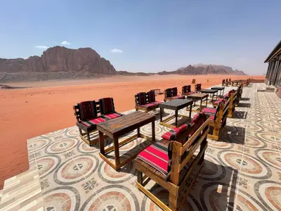 a row of wooden tables and chairs in the desert at Rum Magic Nights in Wadi Rum