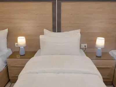 a large white bed with two white pillows and two lights at Beit Alshabaan Inn in Wadi Musa