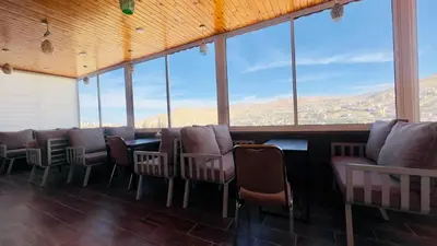 a room with chairs and a table and windows at Beit Alshabaan Inn in Wadi Musa