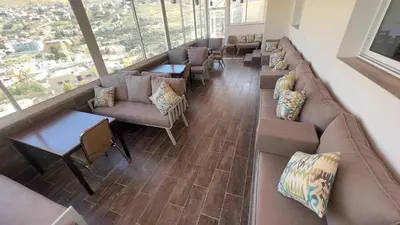 a waiting room with couches and tables and a large window at Beit Alshabaan Inn in Wadi Musa