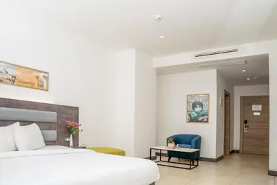 a bedroom with a white bed and a blue chair at Liv Weibdeh Hotel Suites in Amman