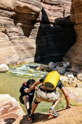 two people in a canyon with a yellow back pack at Safi Kitchen Hostel in Aş Şāfī
