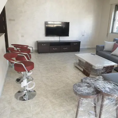 a living room with a couch and a tv and chairs at شقة مفروشة في ام اذينة in Amman
