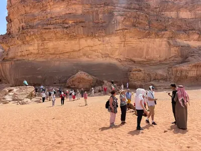 a group of people standing on a beach near a cliff at Wadi Rum Magic Camp in Wadi Rum