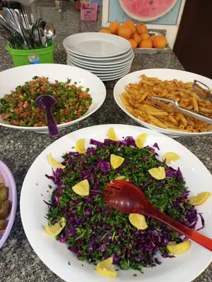 three plates of food on a table with plates of food at Petra voyager Hostel in Wadi Musa