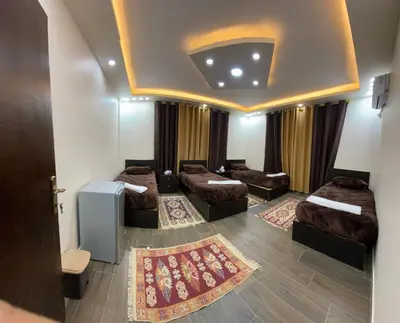 a room with four beds and a room with curtains at Petra Olive House in Wadi Musa