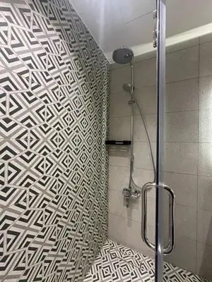 a bathroom with a shower with a geometric patterned wall at Damac Tower Amman - Luxury Studio - استوديوهات فاخرة - داماك عمان العبدلي in Amman