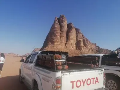 a white truck parked in the desert with luggage at The sun of Wadi Rum in Wadi Rum